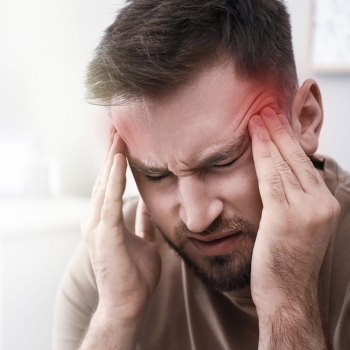 Young man suffering from migraine at home, closeup